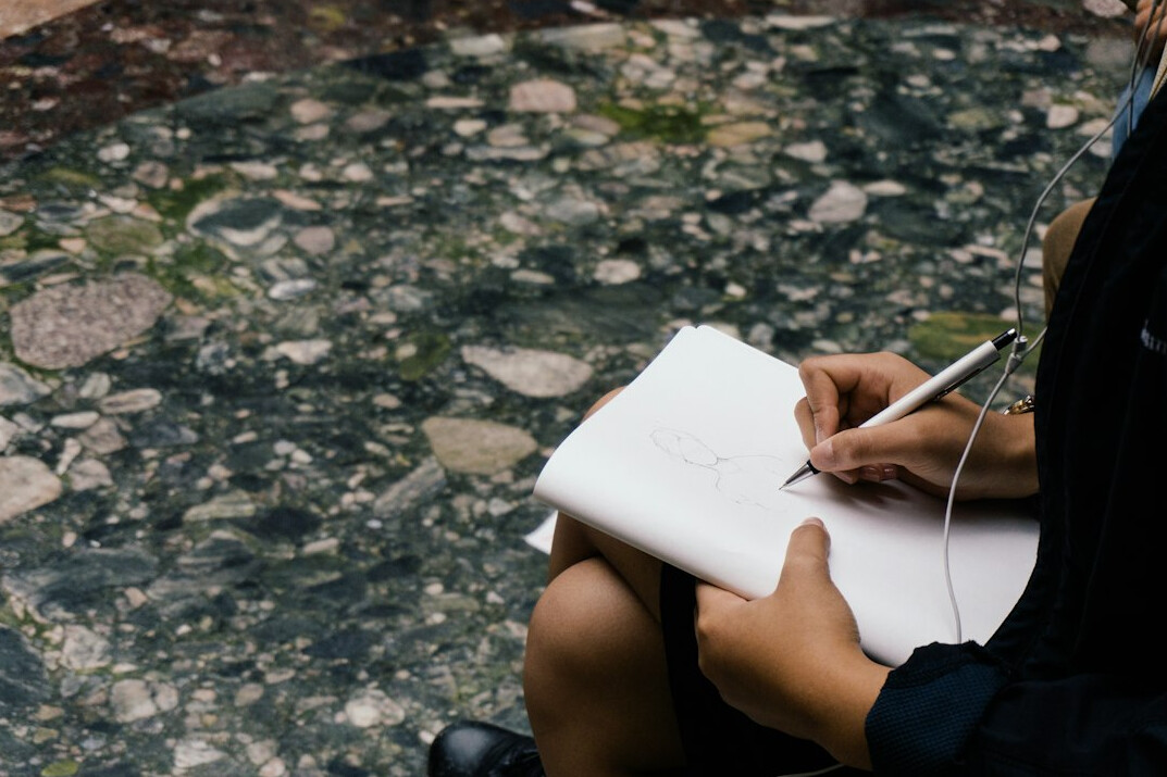 person writing in journal outdoors